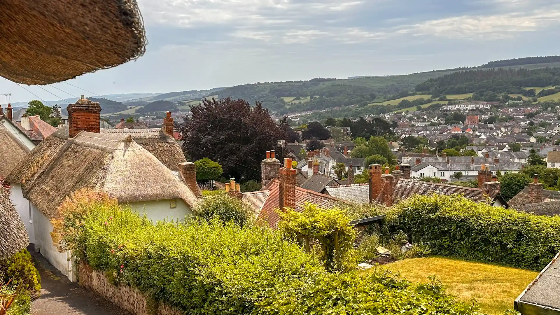 Rooftops and thatched cottages in Minehead with hills of Exmoor in the background.