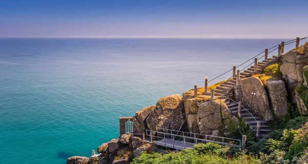 Steps above turquoise waters at Porthcurno, Cornwall — part of the South West Coast Path, popular with self-guided walking holidays from Encounter Walking Holidays.