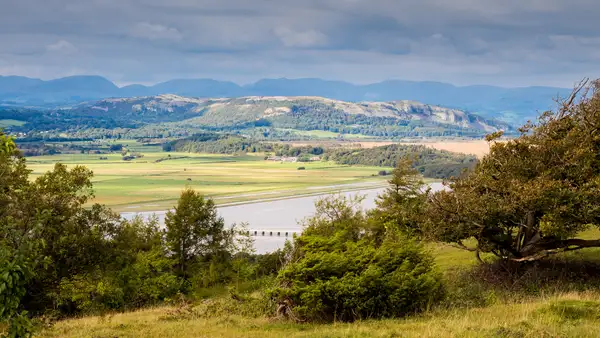View across Morecambe Bay with limestone hills and pastoral countryside in Arnside and Silverdale National Landscape.