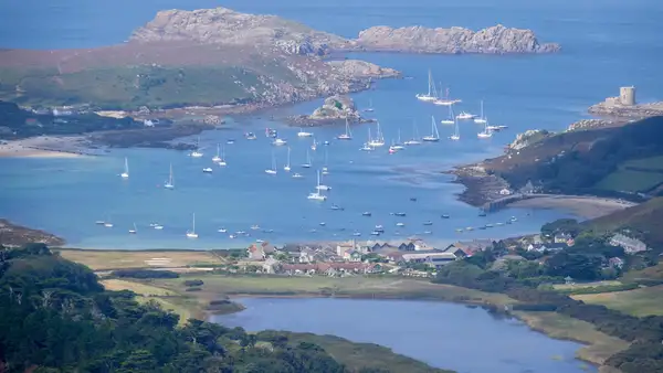 Island harbour and granite headlands in the Isles of Scilly National Landscape with boats anchored in sheltered waters.