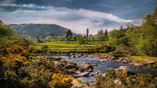 River and glacial valley landscape at Glendalough in Wicklow Mountains National Park with monastic tower in the distance.
