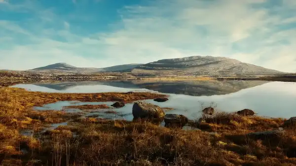 Limestone hills and seasonal wetland reflected in still water in The Burren National Park.