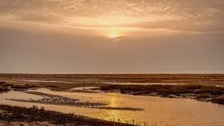 Saltmarsh and tidal channels at sunset near Holme-next-the-Sea on the Norfolk coast, with open skies and low coastal light.