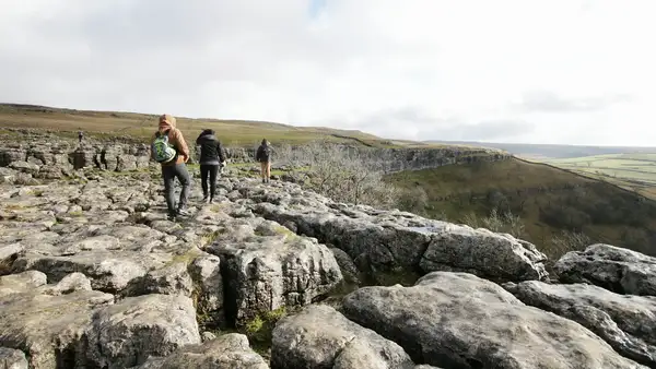 Walkers crossing the limestone pavement at Malham Cove in the Yorkshire Dales National Park, North Yorkshire.