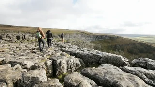 Walkers crossing the limestone pavement at Malham Cove in the Yorkshire Dales National Park, North Yorkshire.