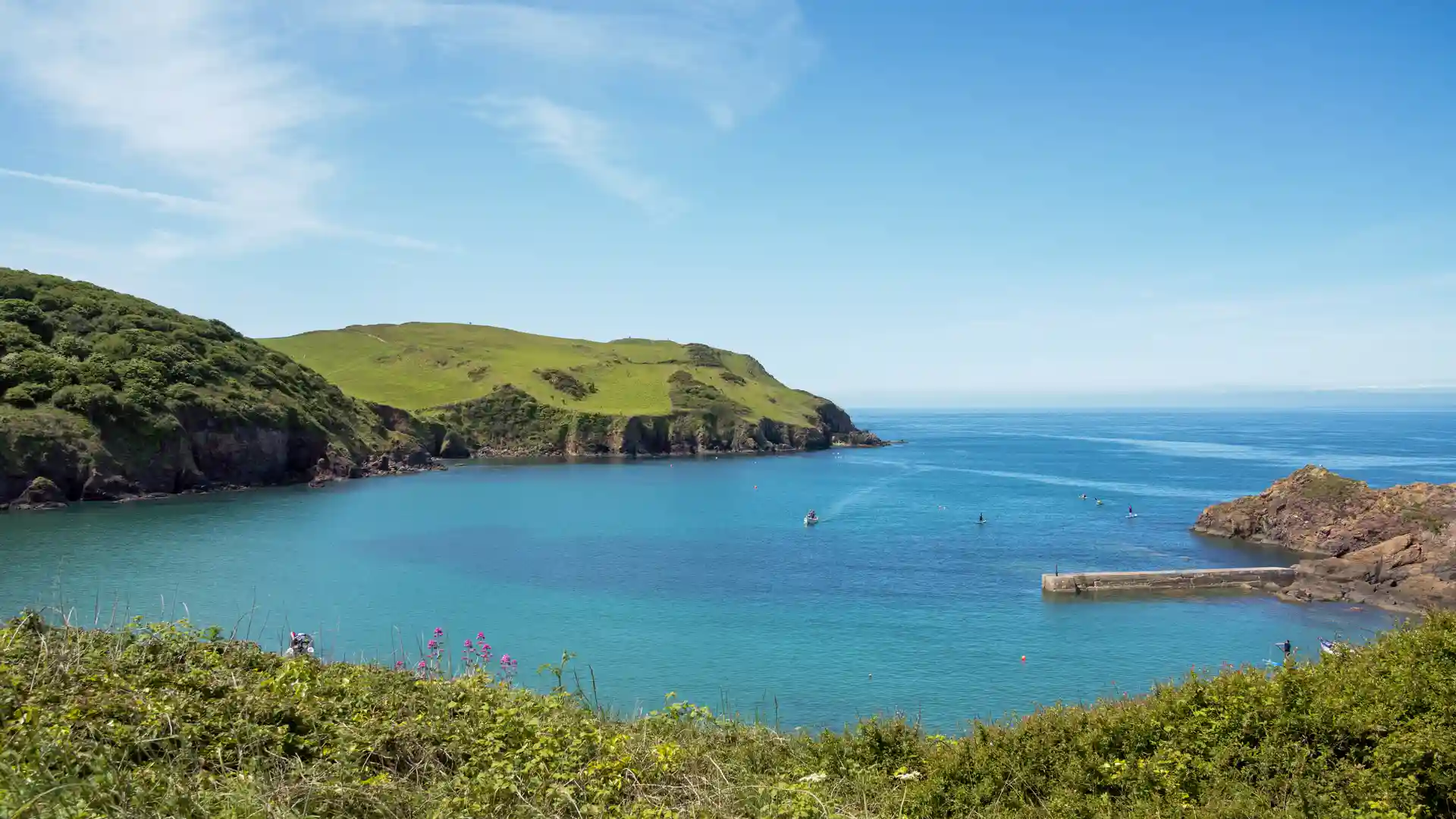 Sheltered coastal bay and headland walking route in the South Devon National Landscape, England.