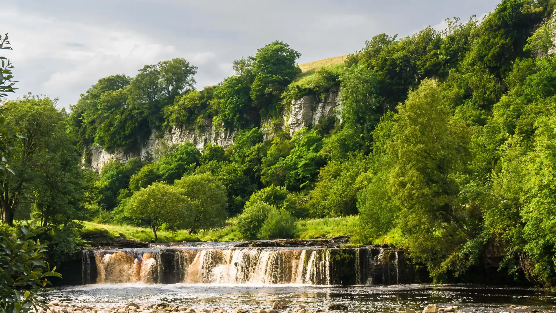 Waterfall and limestone cliffs along the Coast to Coast Path in the Yorkshire Dales.