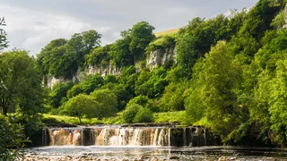 Waterfall and limestone cliffs along the Coast to Coast Path in the Yorkshire Dales.
