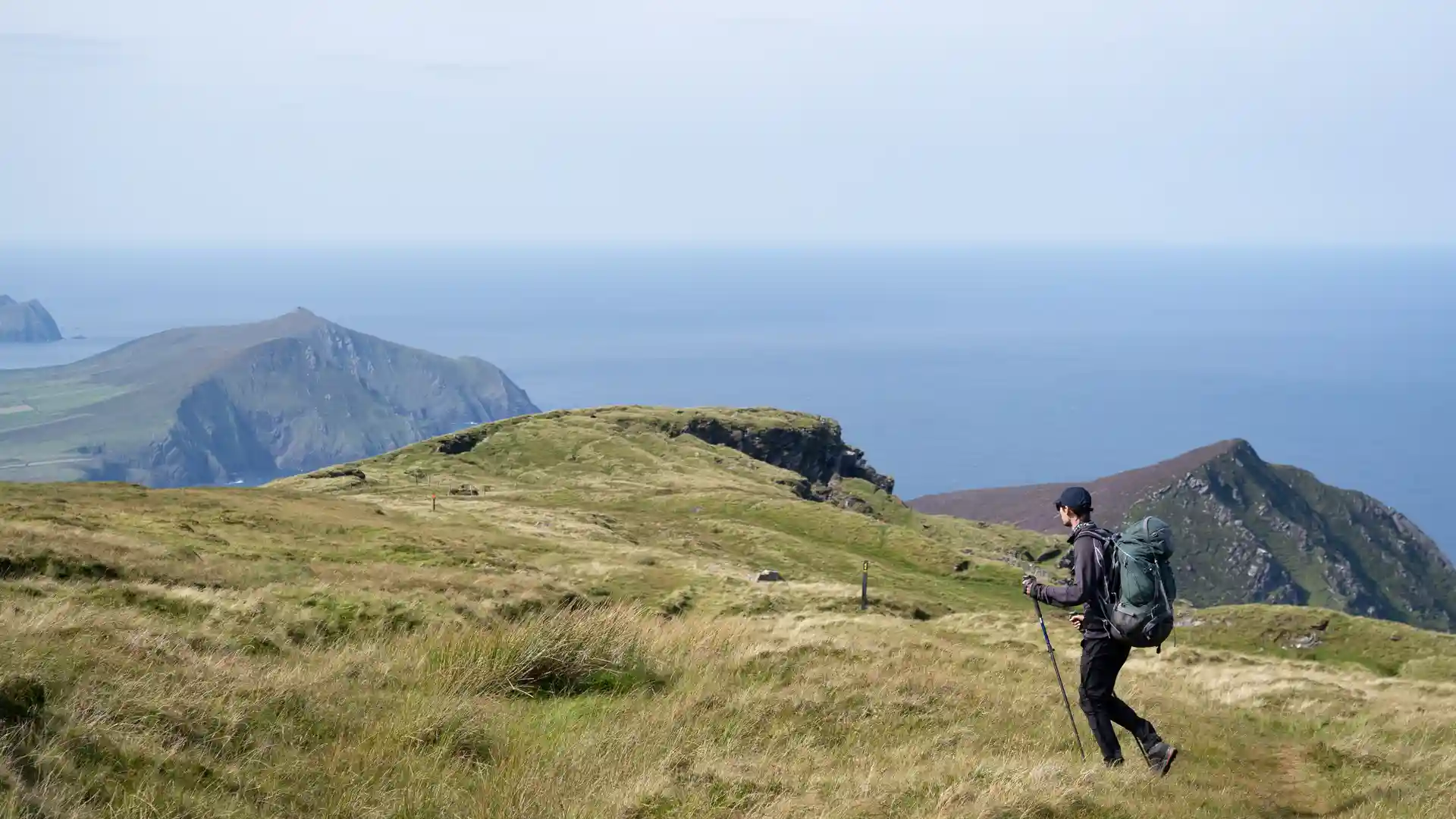Walker with backpack on coastal headland along the Dingle Way in County Kerry.