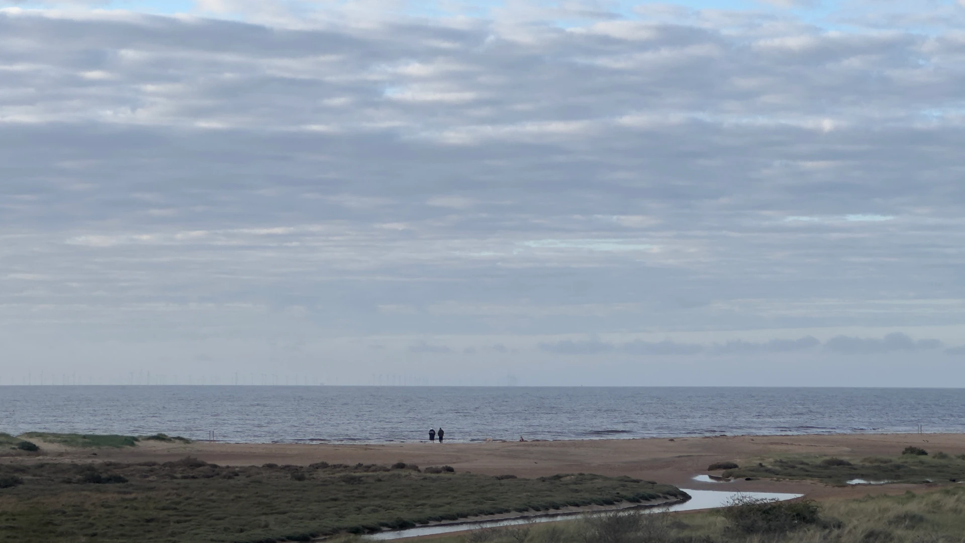 Wide beach at Holme-next-the-Sea on the Norfolk Coast Path under a clouded sky with open coastal views.