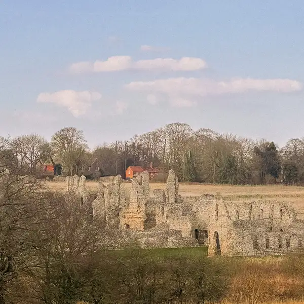Castle Acre Priory ruins with surrounding fields, stone buildings, and the village church tower in the distance — a key landmark along the Peddars Way in Norfolk.