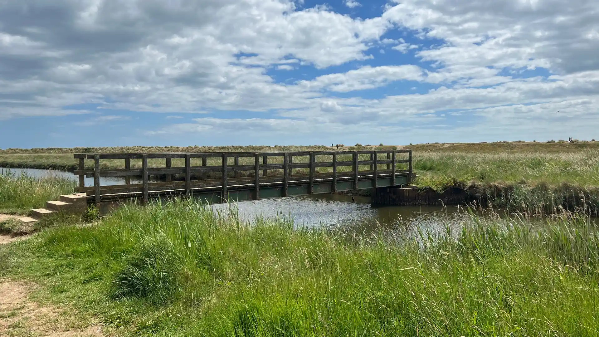 Footbridge crossing coastal marshes along the Suffolk Coast Path beneath wide East Anglian skies.