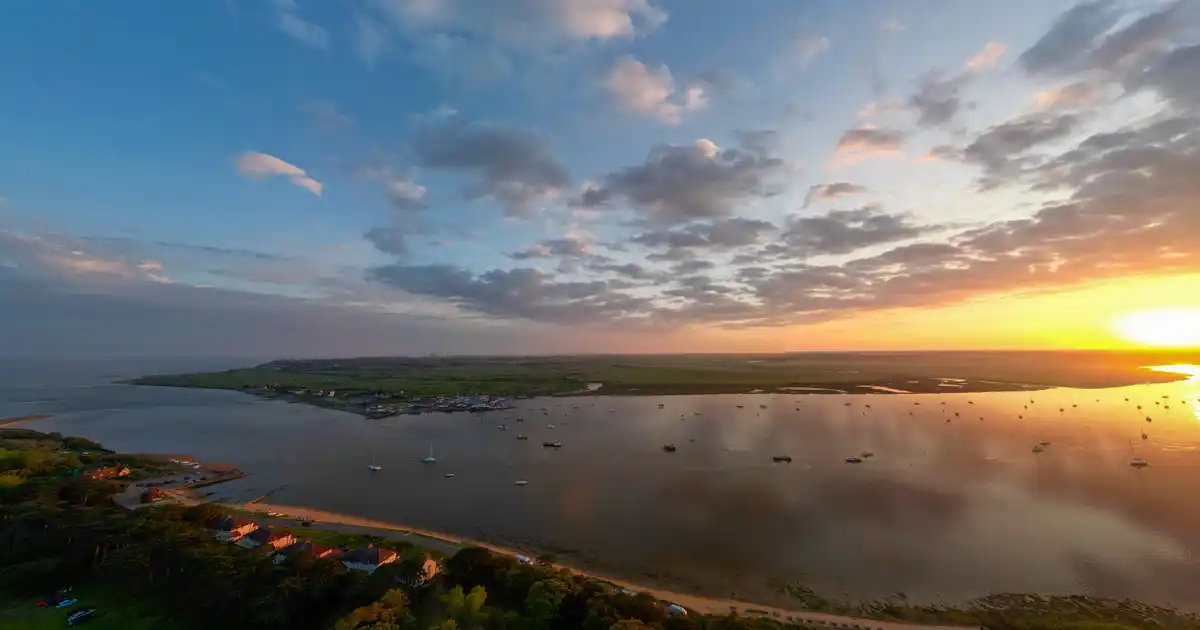 Sunset over an estuary on the Suffolk Coast, with boats moored across the water.