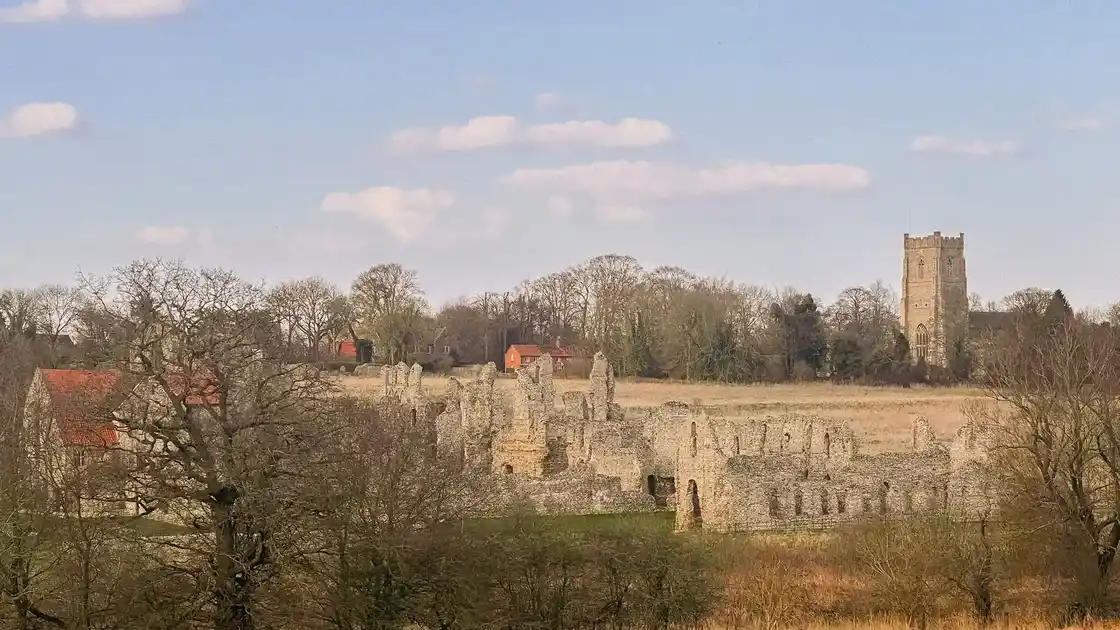 Castle Acre Priory ruins with surrounding fields, stone buildings, and the village church tower in the distance — a key landmark along the Peddars Way in Norfolk.