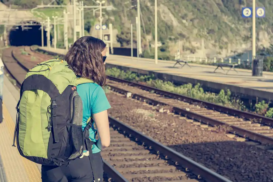 Walker with a backpack waiting at a rural railway station before travelling to a walking trail.
