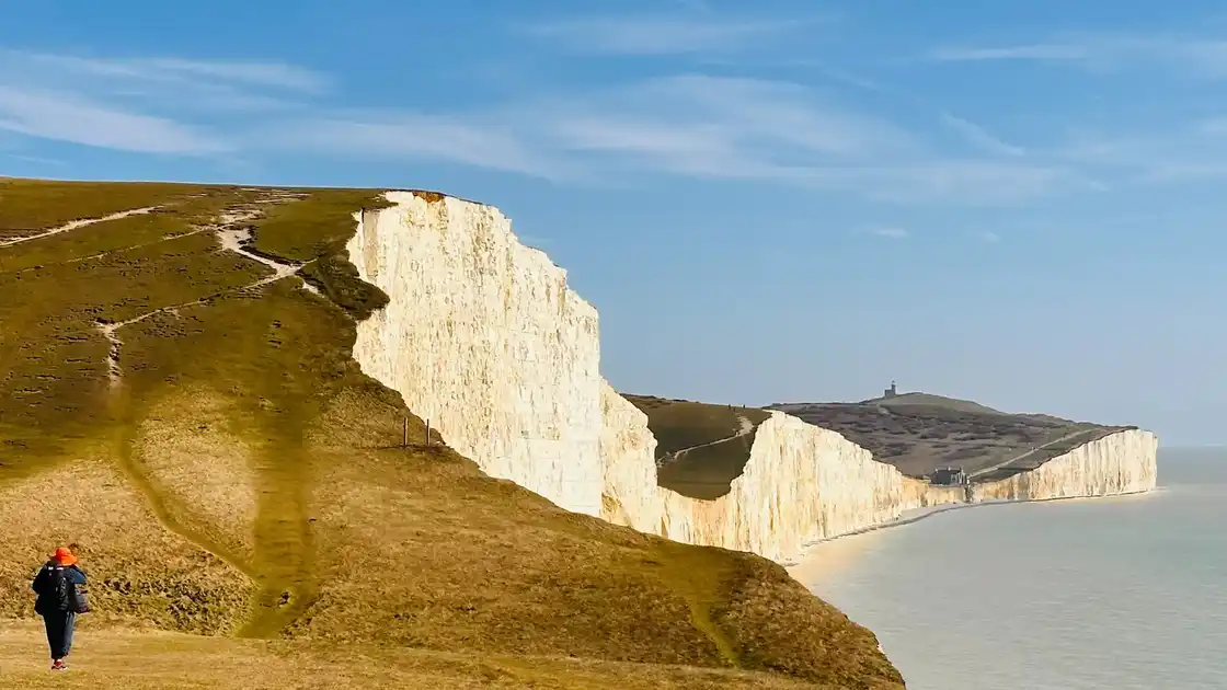 Walker on the South Downs Way overlooking the white cliffs of the Seven Sisters on the Sussex coast.