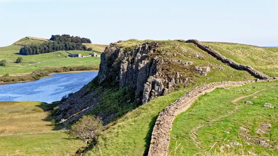 Hadrian’s Wall running along the Whin Sill above Crag Lough in Northumberland, with walkers on the ridgeline of the UNESCO World Heritage Site.