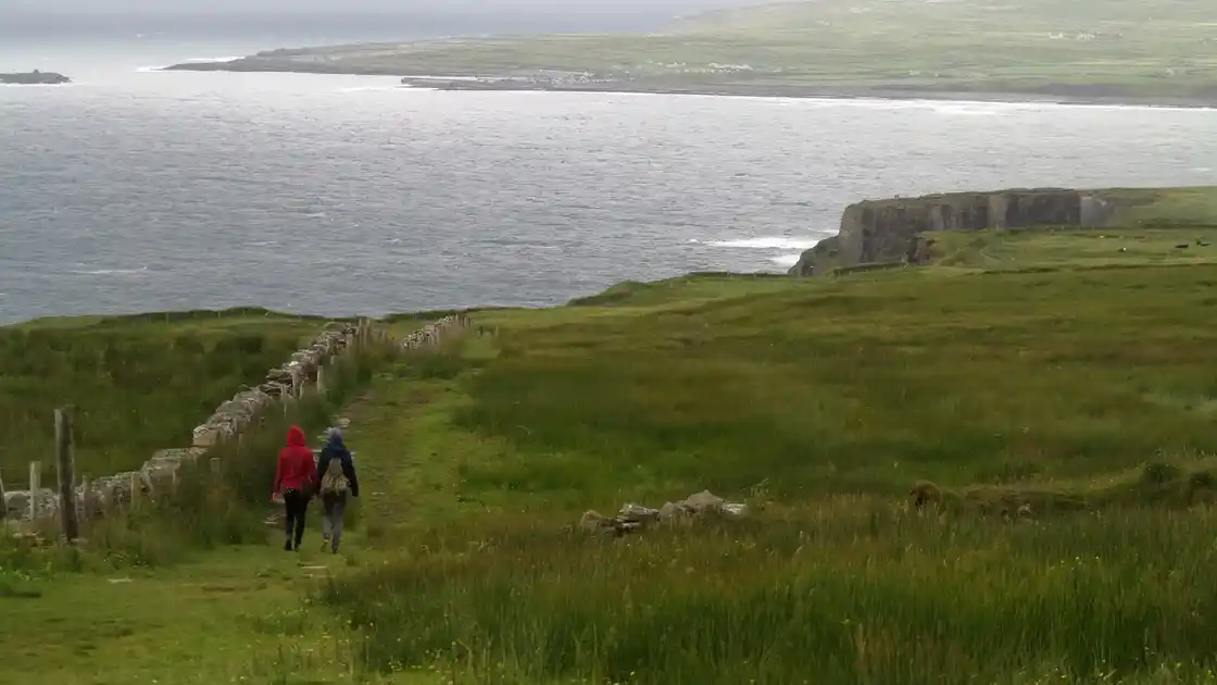 Walkers following a grassy track through limestone landscape near the Burren, County Clare, Ireland.