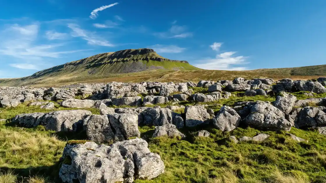 Limestone pavement with Pen-y-ghent rising above the Ribble Valley in the Yorkshire Dales National Park.