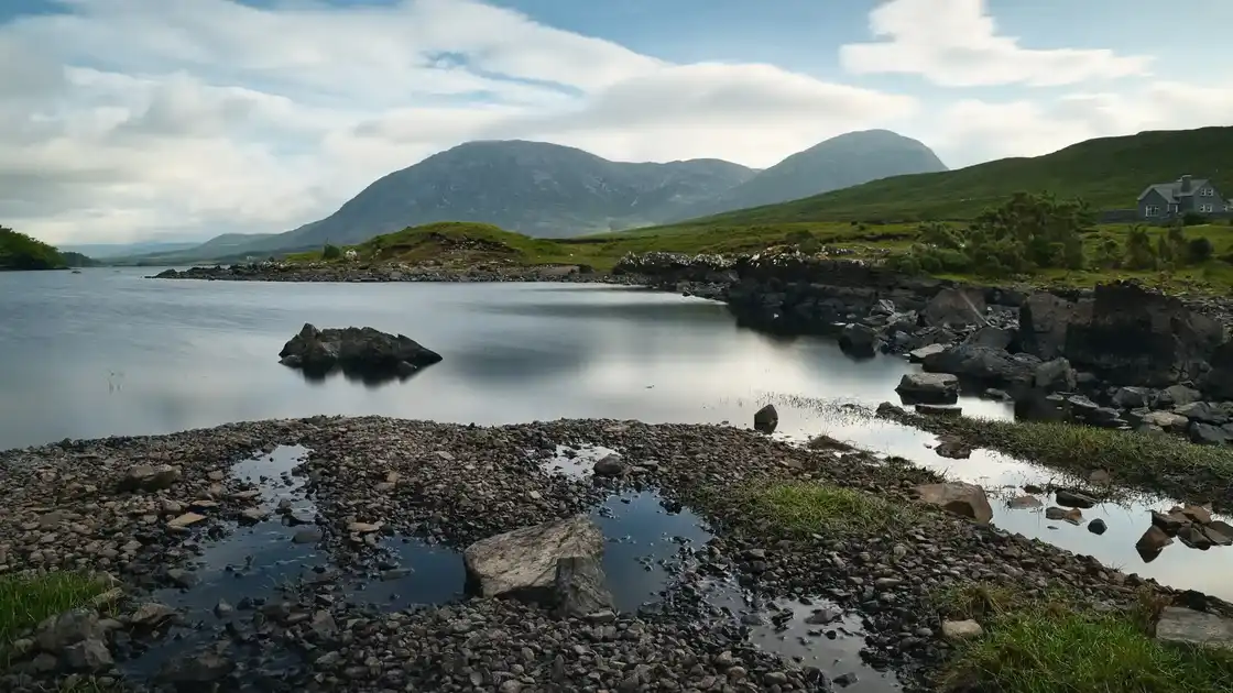 Rocky shoreline and calm inlet with mountains near the Western Way in Connemara, Ireland.