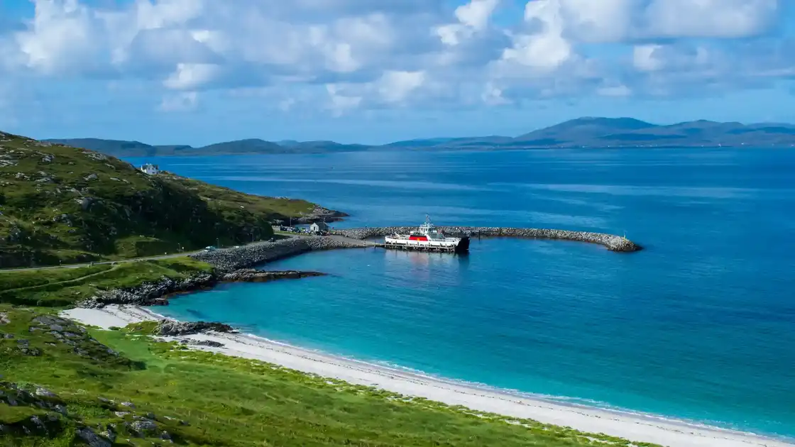 Berneray ferry harbour on the Hebridean Way with sandy beach and coastal hills, Outer Hebrides, Scotland.
