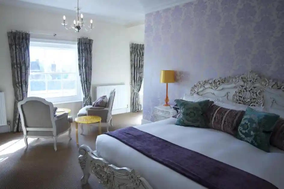 Guest bedroom with ornate bed and seating area at The Angel Hotel in Bury St Edmunds.