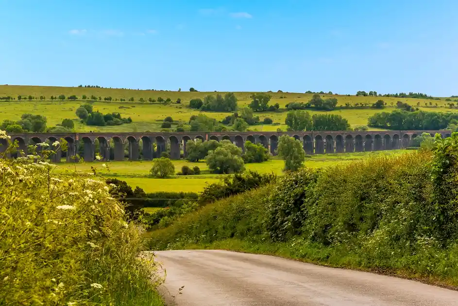 Harringworth Railway Viaduct crossing the green countryside of the Welland Valley in Northamptonshire, with rolling hills and farmland beyond.