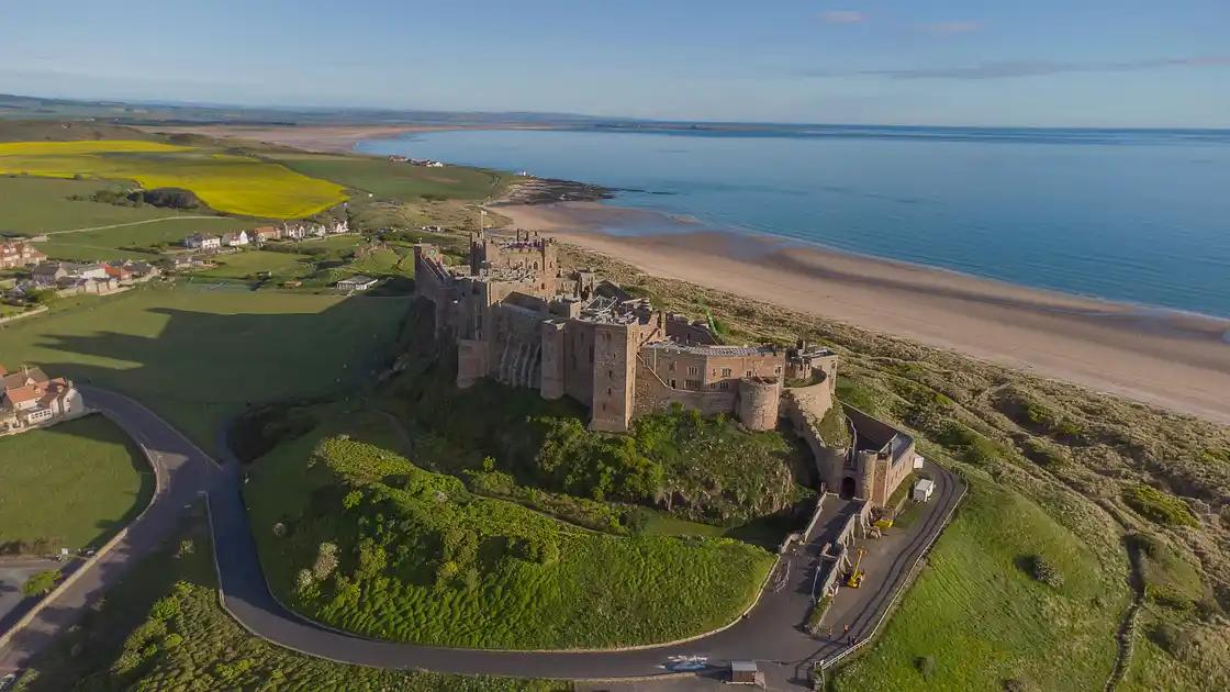 Aerial view of Bamburgh Castle overlooking the sandy beach and coastline of Northumberland, North East England.