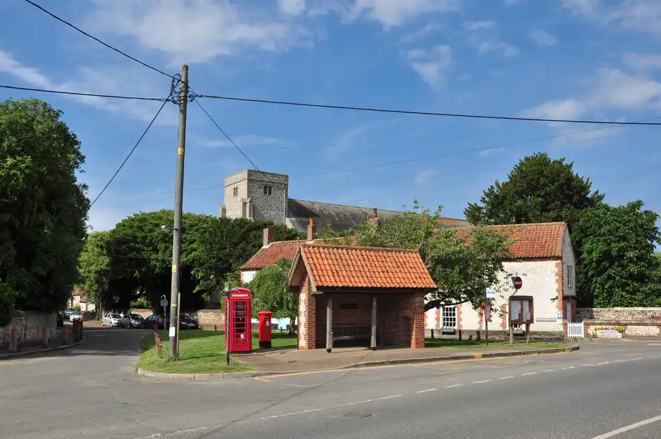 Village centre of Thornham on the Norfolk coast, with traditional cottages, a red telephone box and the parish church in the background.
