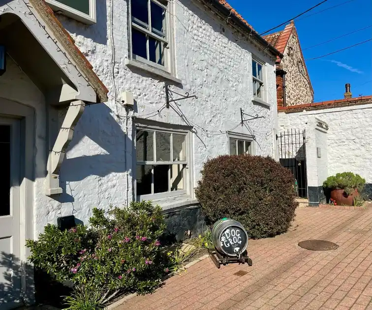 Whitewashed exterior and paved courtyard at The Chequers Inn in Thornham, Norfolk, with traditional windows and planted shrubs.