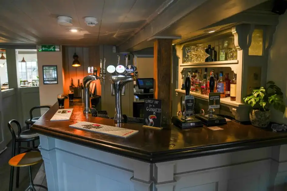 Traditional bar interior at The Chequers Inn in Thornham, Norfolk, with wooden counter, beer taps and shelves of spirits.