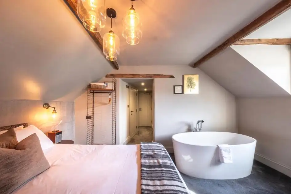 Guest bedroom at The Chequers Inn in Thornham, Norfolk, featuring exposed wooden beams, a double bed and a freestanding bathtub.
