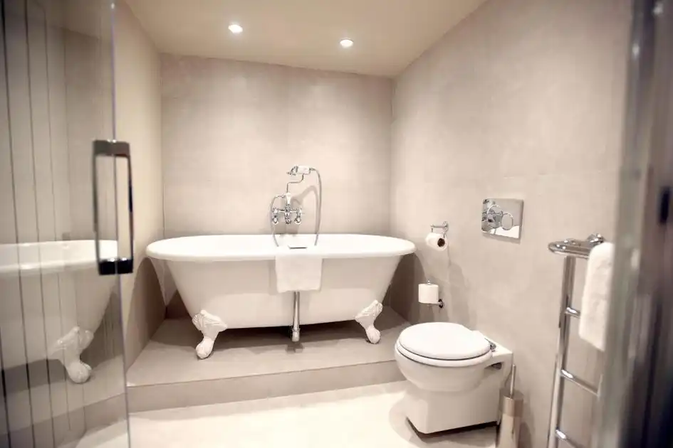 En-suite bathroom at The Lifeboat Inn in Thornham, Norfolk, featuring a freestanding roll-top bathtub, glass shower enclosure and modern fittings.