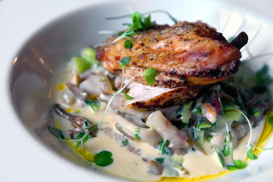 Restaurant dish at The Lifeboat Inn in Thornham, Norfolk, featuring roasted meat served with mushrooms, greens and a creamy sauce.