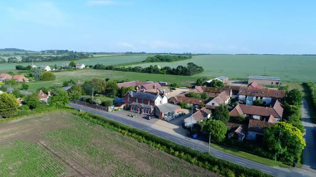 Aerial view of Titchwell Manor Hotel in Titchwell, Norfolk, showing the hotel buildings beside the coastal road, surrounded by farmland and countryside.