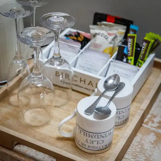 Guest room refreshment tray at Cley Windmill in Cley-next-the-Sea, Norfolk, featuring drinking glasses, ceramic mugs, teaspoons and a selection of teas, coffee and snacks.
