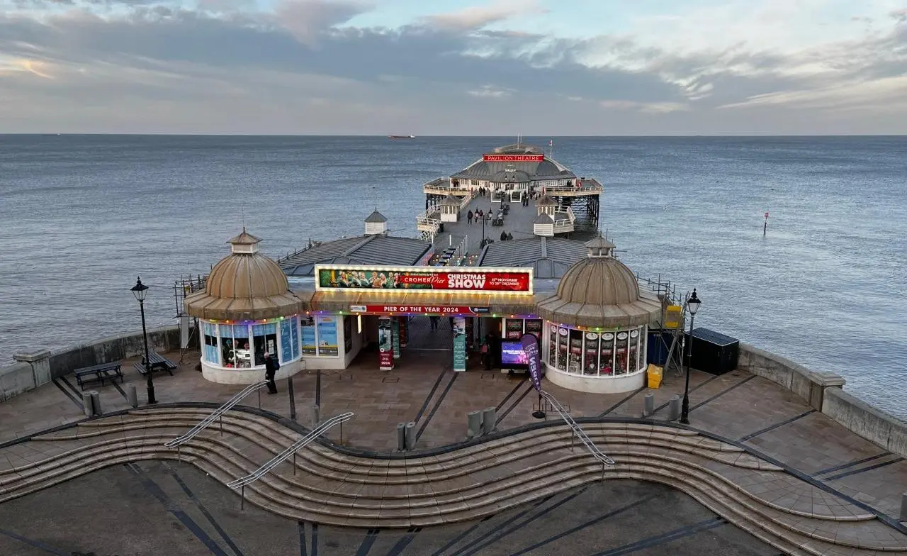 Cromer Pier on the Norfolk coast, showing the historic pier entrance, domed pavilions, lifeboat station and Pavilion Theatre extending into the North Sea.