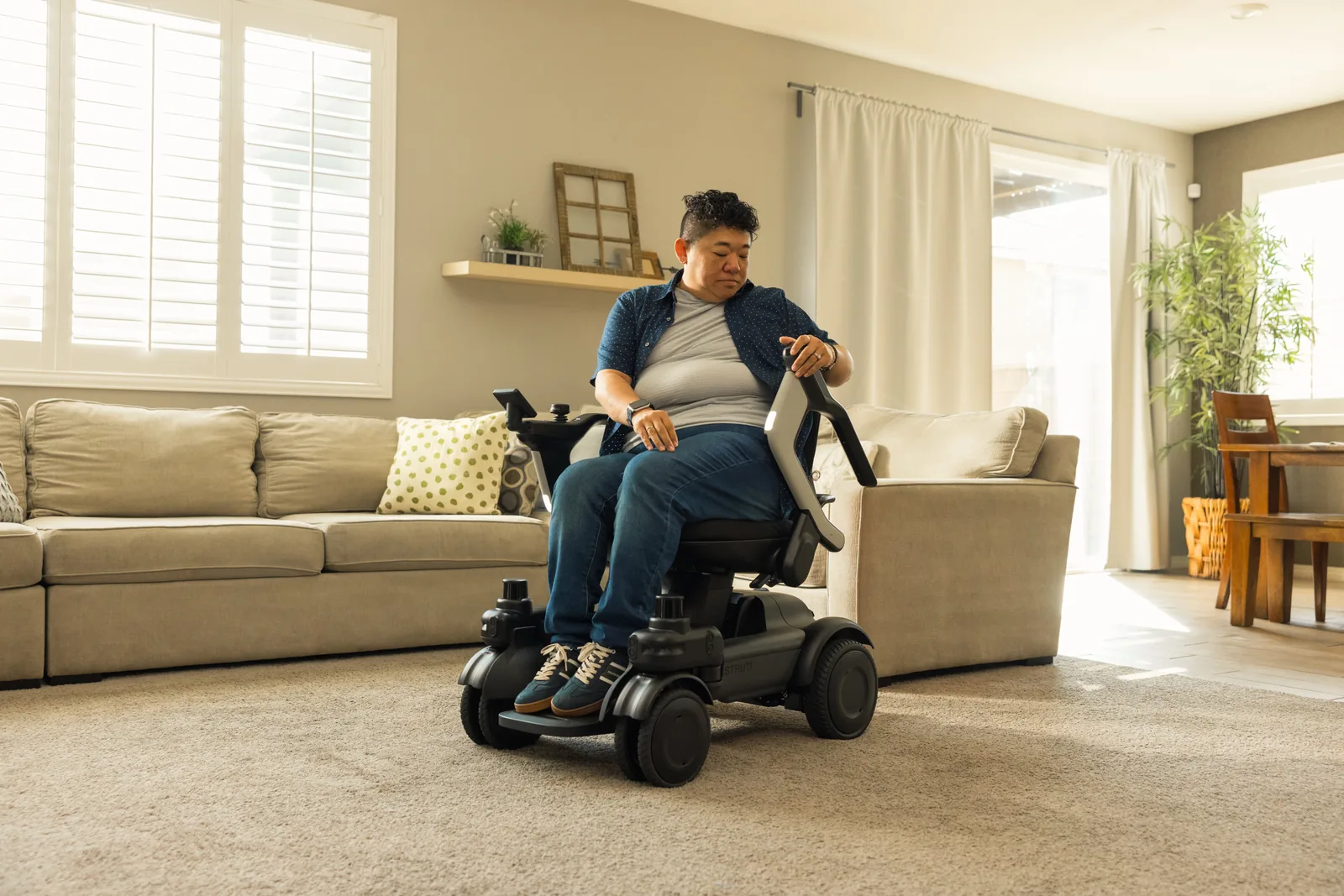 Utilisateur installé dans le Strutt ev¹e dans son salon, accoudoirs relevables