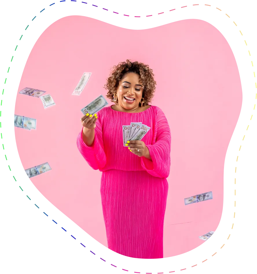 Smiling woman in bright pink dress holding and tossing US hundred-dollar bills against a pink background.