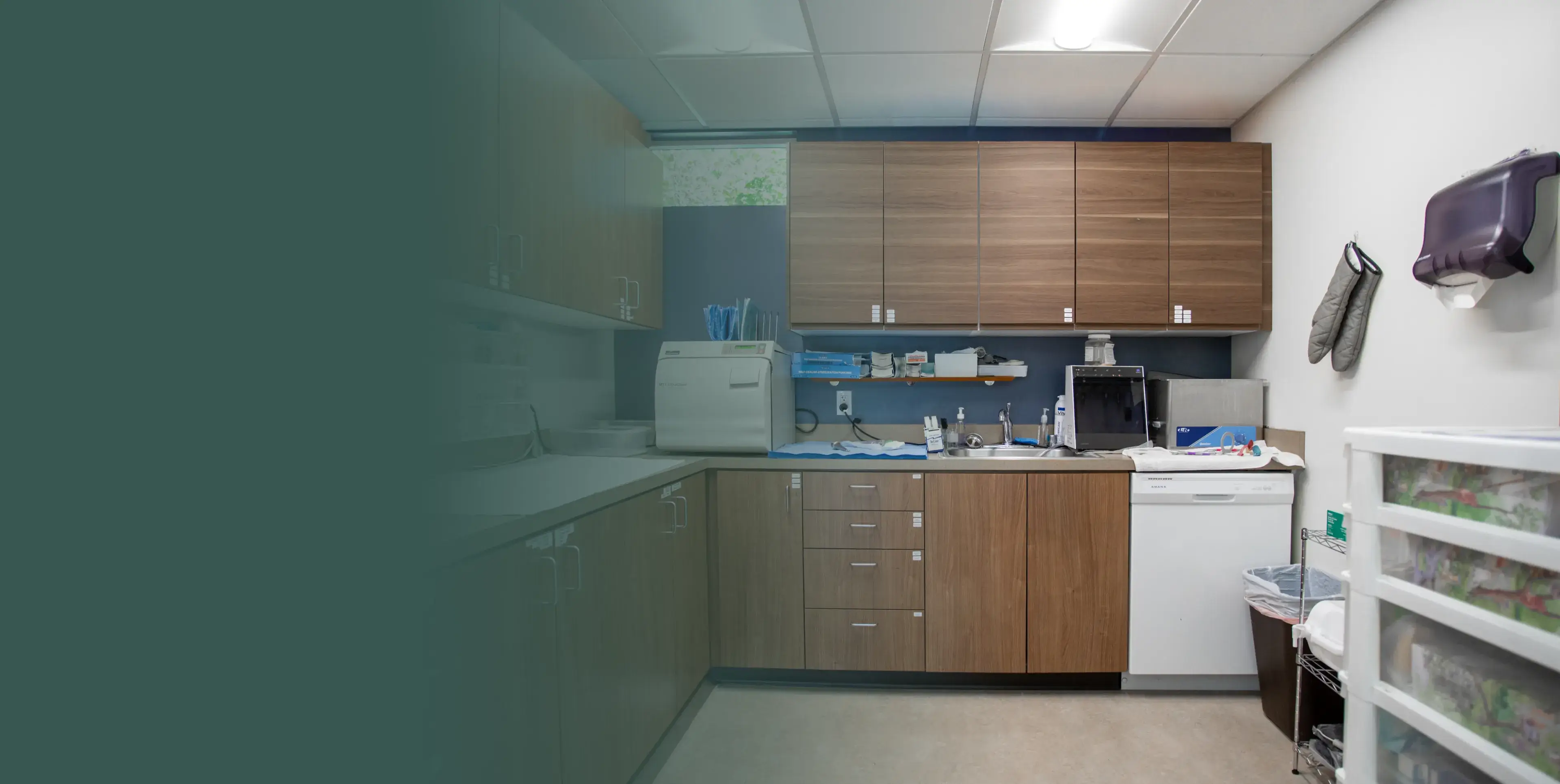 A small medical room with wooden cabinets, countertop, and medical equipment neatly arranged.