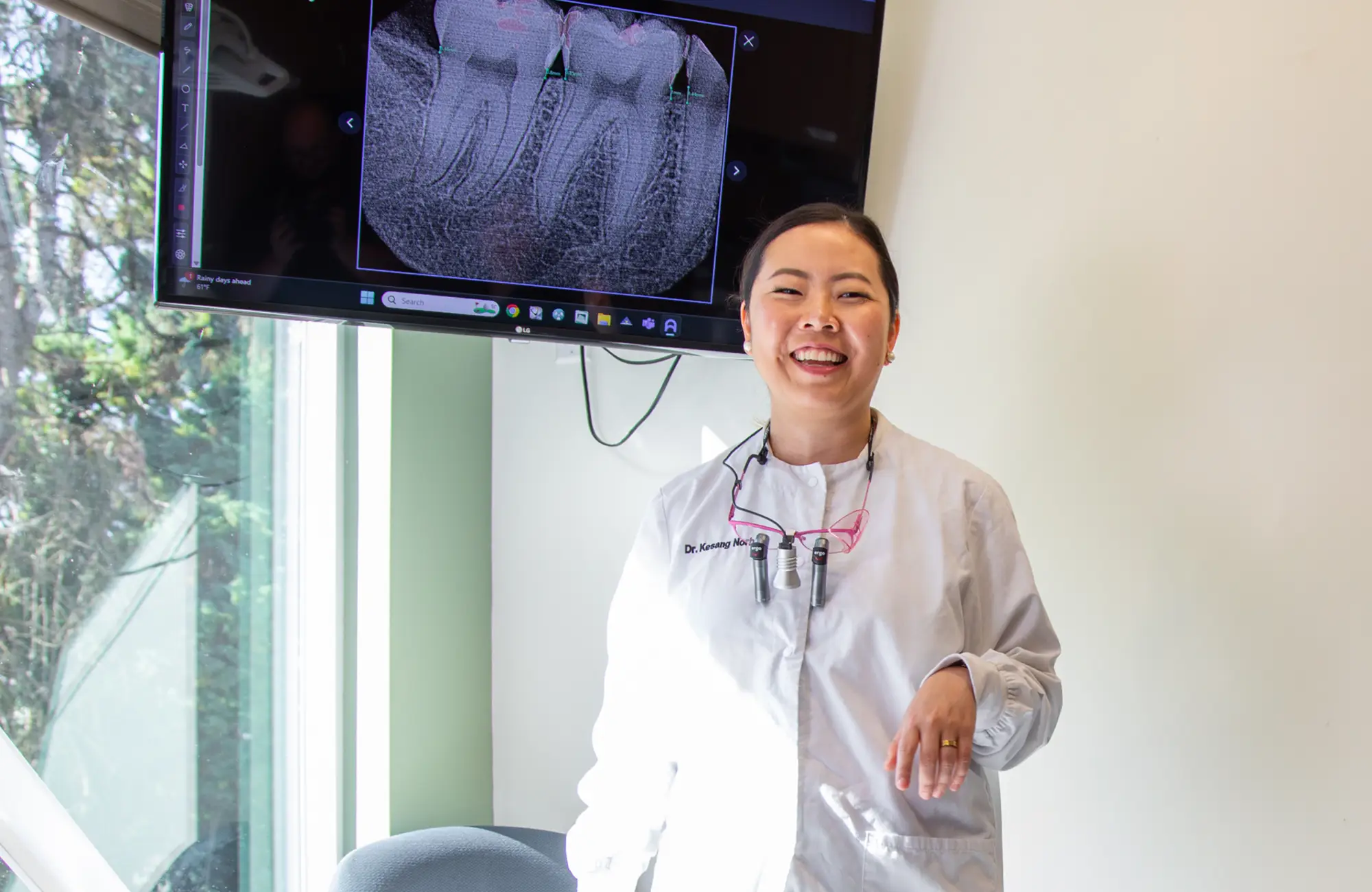 A dentist discusses dental X-rays with a patient sitting in a chair.
