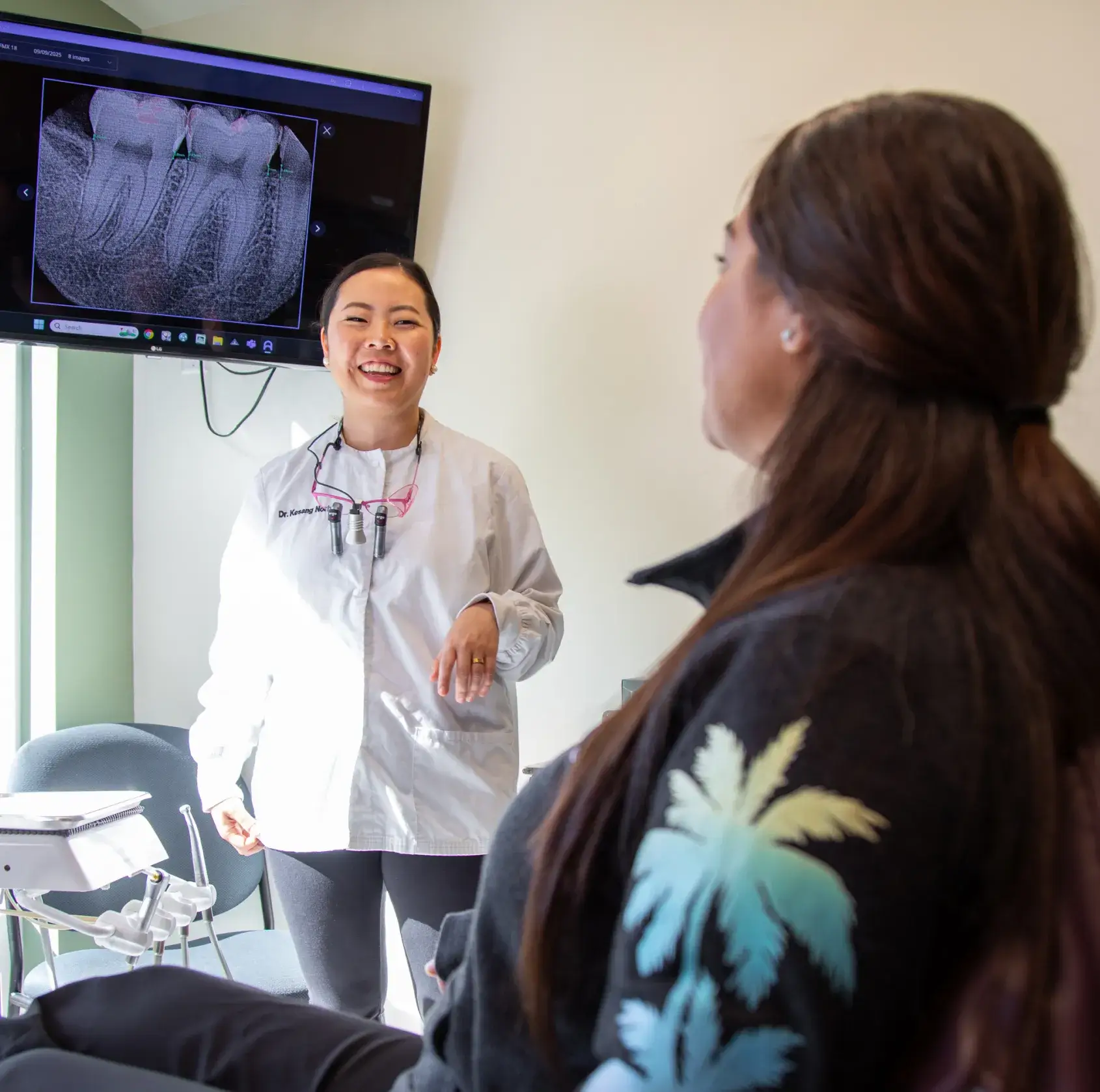 A dentist discusses dental X-rays with a patient in an examination room.