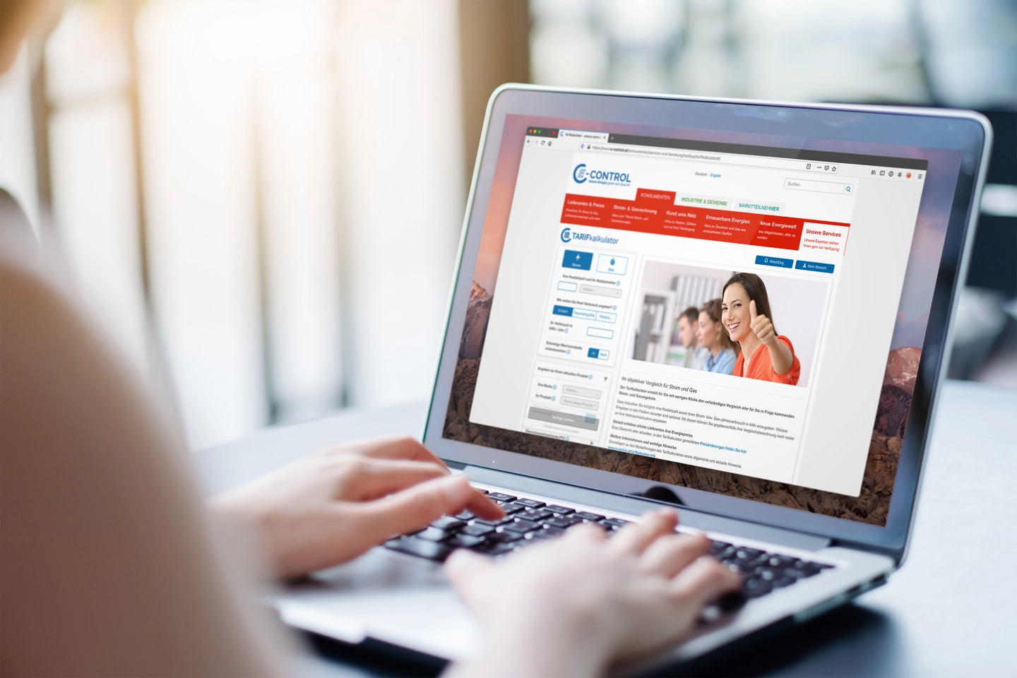 Person tippt auf einem Laptop, auf dessen Bildschirm ein Tarifkalkulator der Website E-Control zu sehen ist.