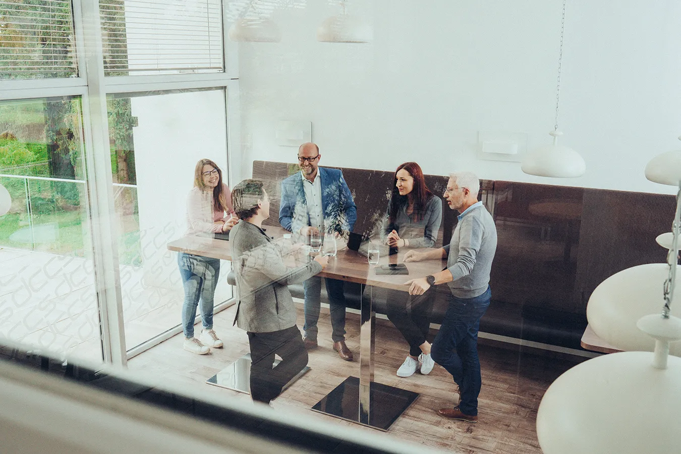 Fünf Personen stehen um einen hohen Tisch in einem modernen Raum und führen ein Gespräch.