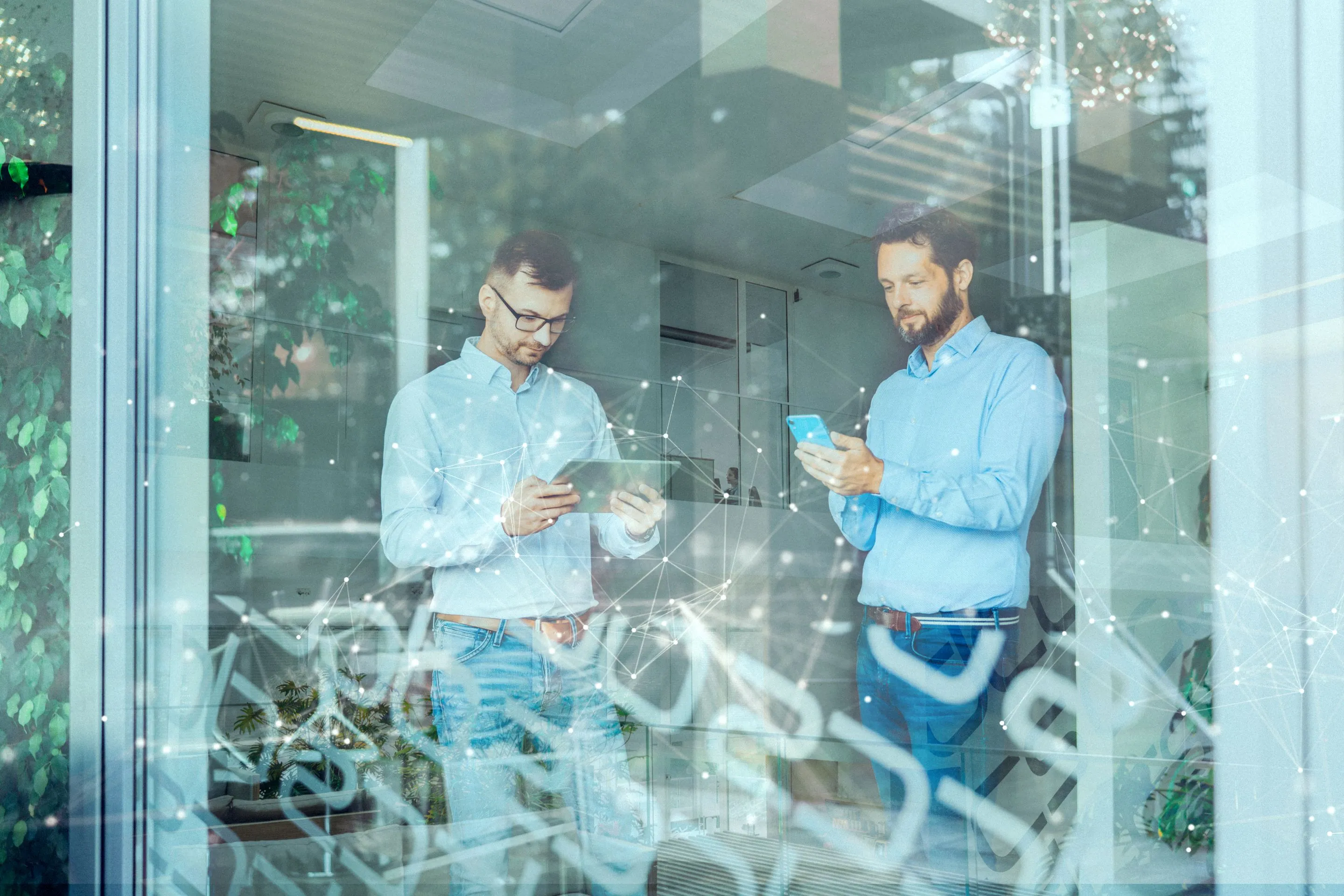Zwei Männer in einem Büro, die auf digitale Geräte schauen, umgeben von vernetzten Lichtpunkten als Symbol für digitale Technologie.