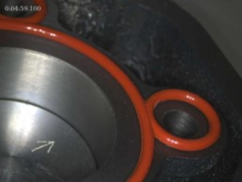 Nahaufnahme einer Metallfläche mit einem roten Dichtungsgummi und einer eingravierten weißen Markierung.