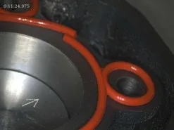 Nahaufnahme eines schwarzen Metallteils mit roten Dichtungen und einer eingebetteten Metallfeder.