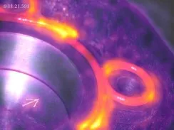 Thermisches Bild einer Maschine mit hellen orangefarbenen und gelben Wärmebereichen an Metallteilen.