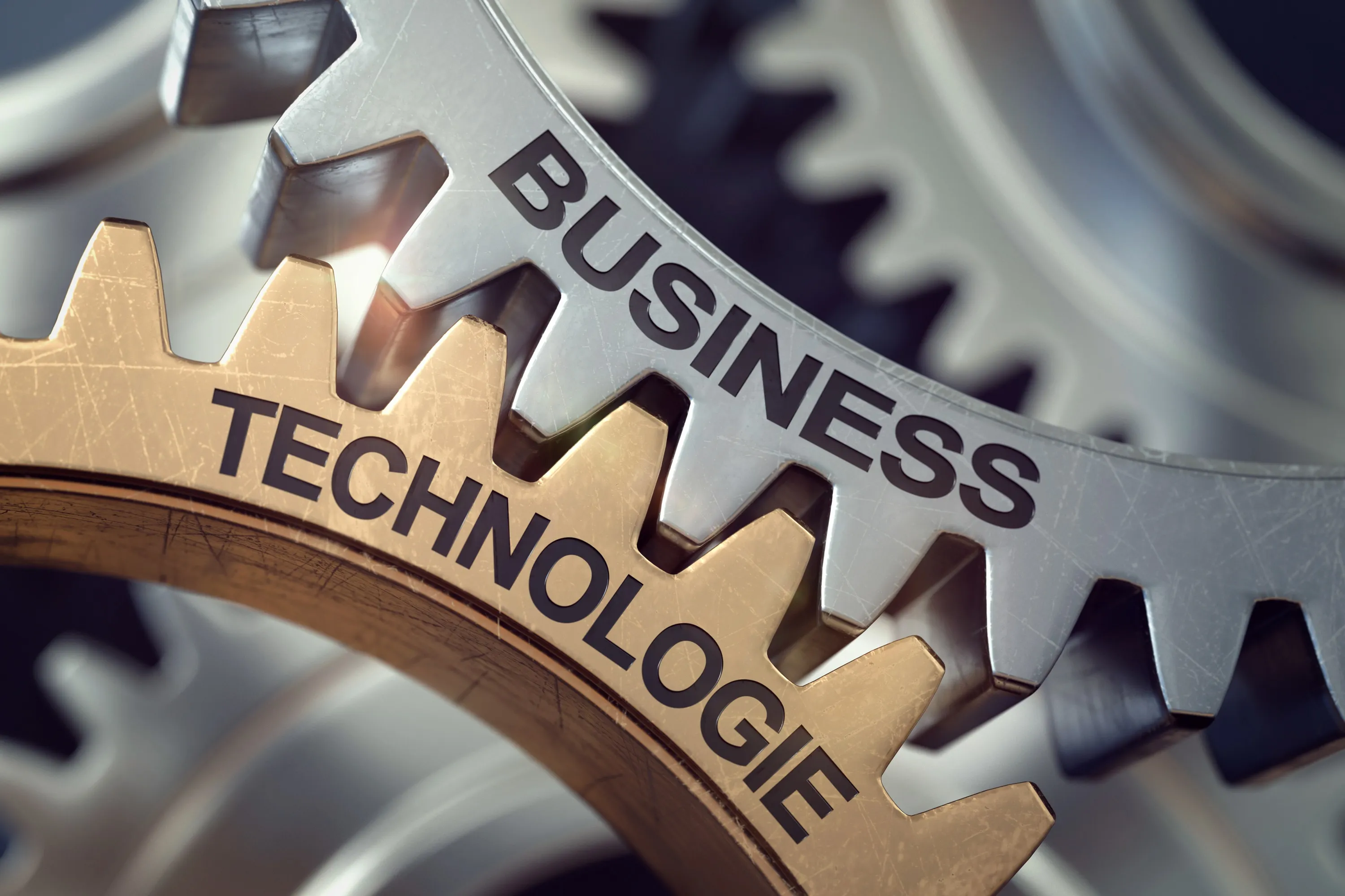 Nahaufnahme von ineinandergreifenden Zahnrädern mit den Worten Business und Technologie.