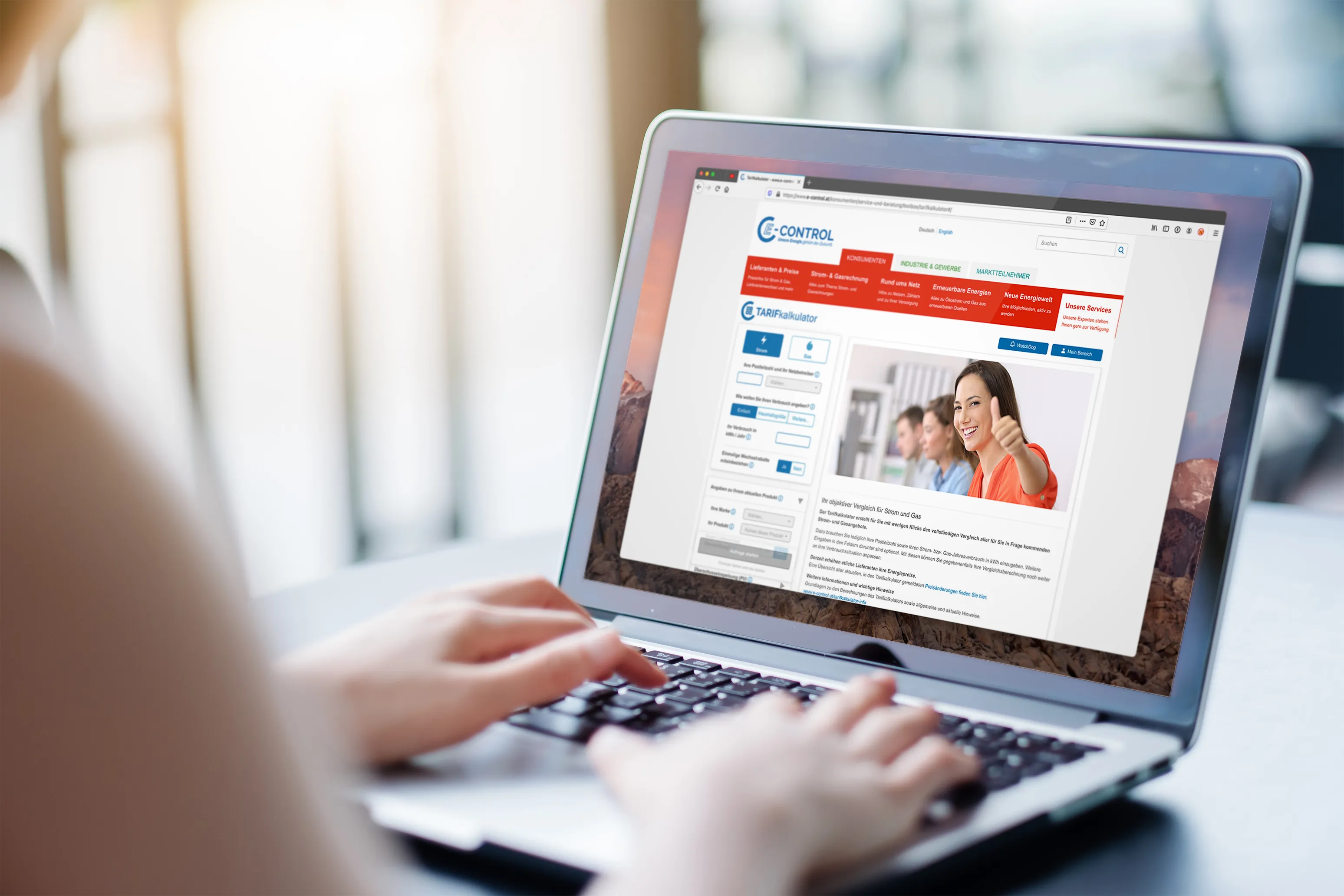 Person tippt auf Laptop mit geöffneter Webseite eines Tarifkalkulators für Strom und Gas, zeigt lächelnde Frau mit Daumen hoch.